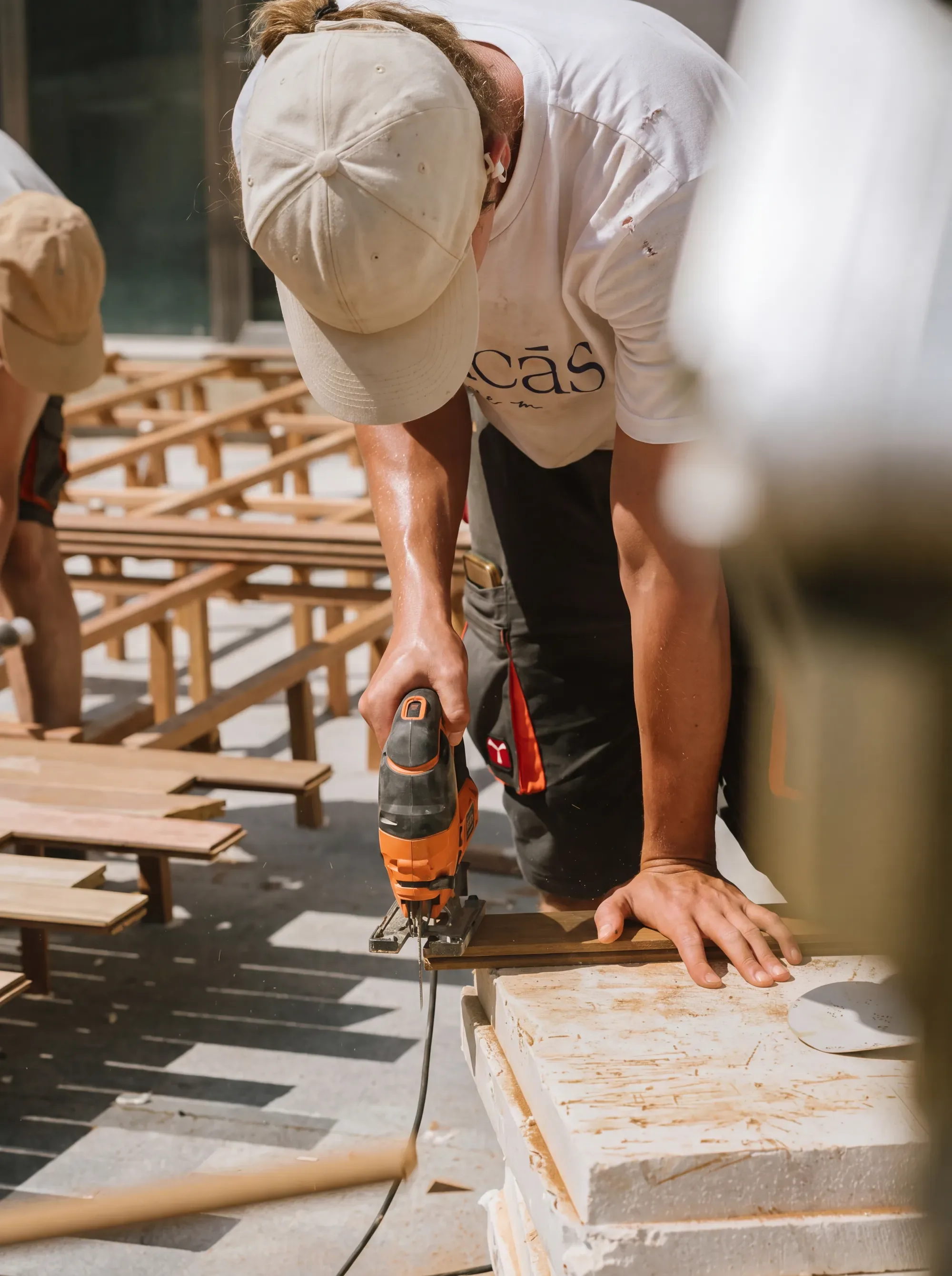 A worker cutting timber on site during an installation project